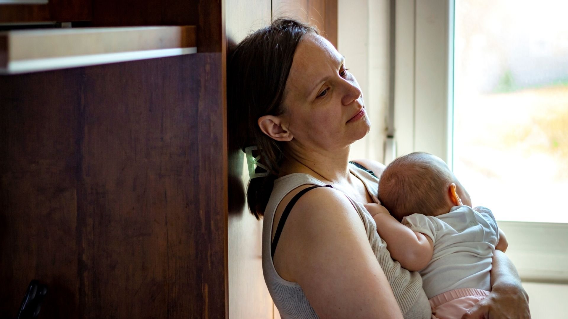 Sleep deprived mum holding her baby against her chest