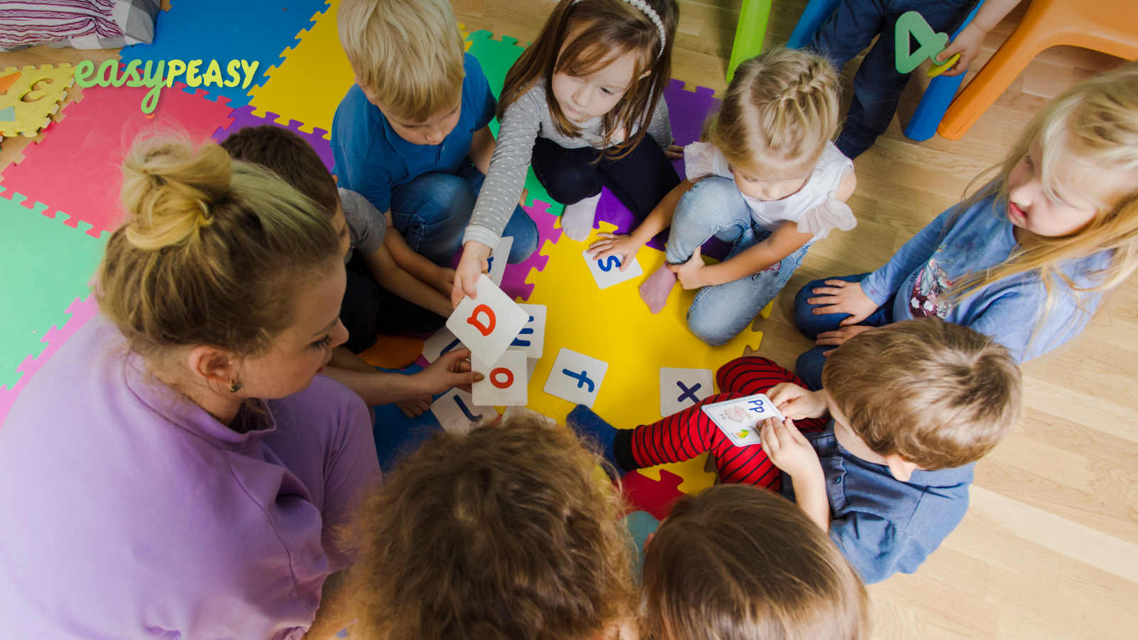 smiling toddler wearing a pink t-shirt and building a LEGO tower