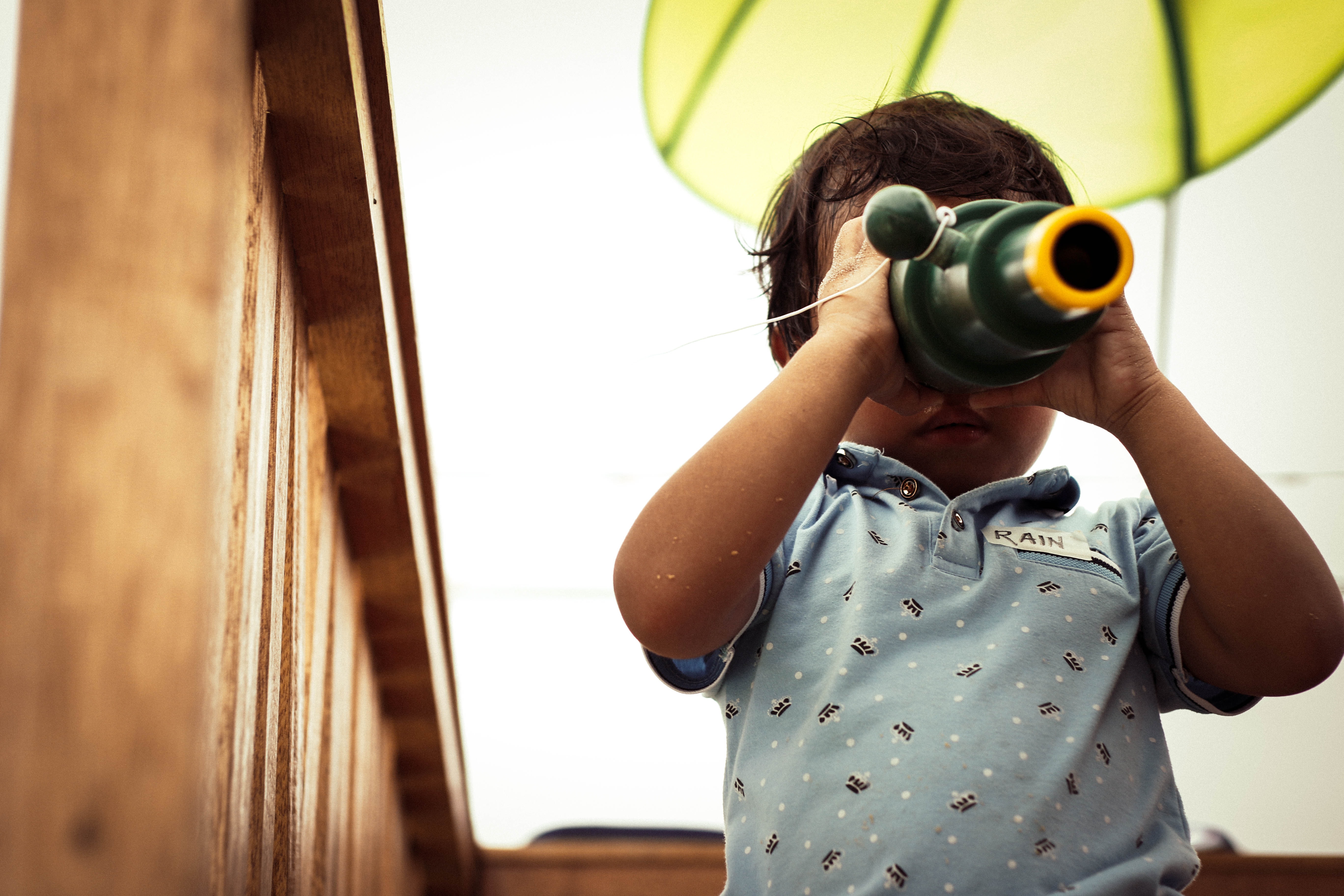 Child sitting on the stairs, looking through a toy telescope