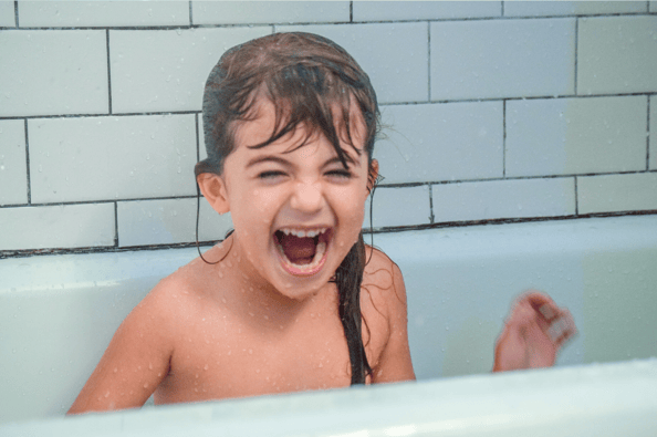 Laughing child with wet hair in the bath