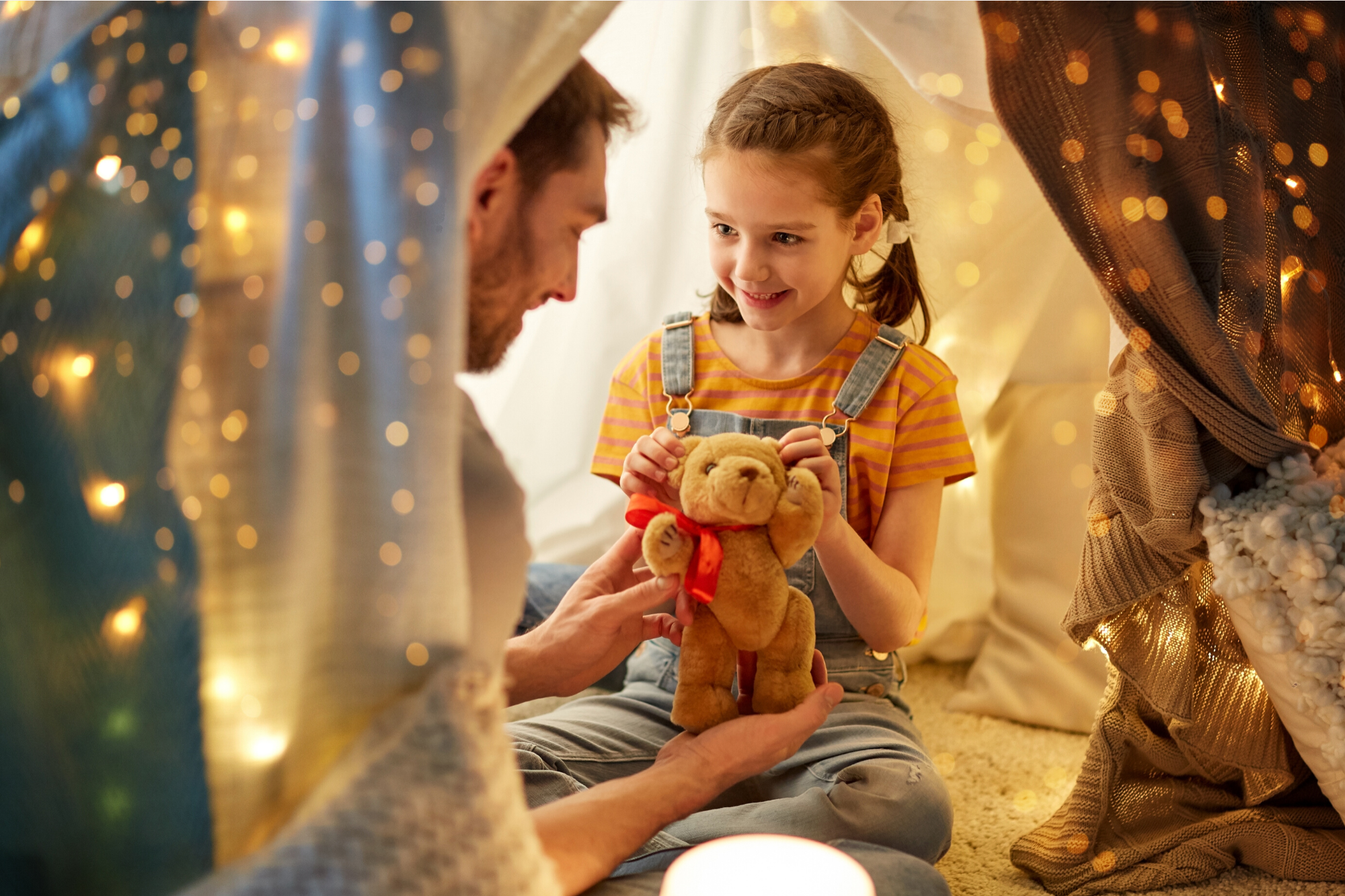 Father and his toddler playing with a brown teddy bear at home