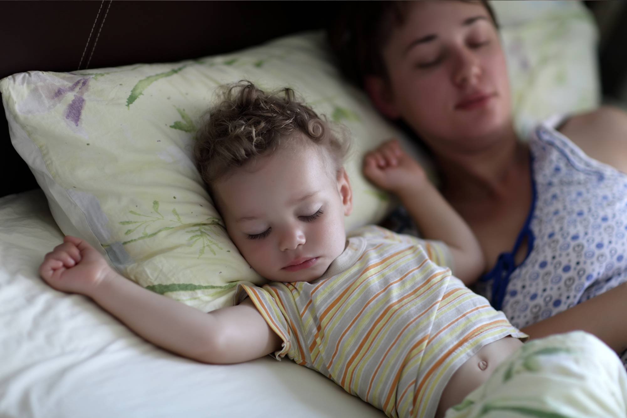 Mother and toddler asleep in bed together 