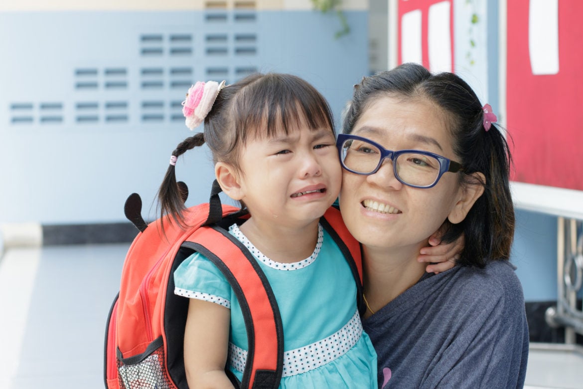 A child crying at the school gates or walking with mother