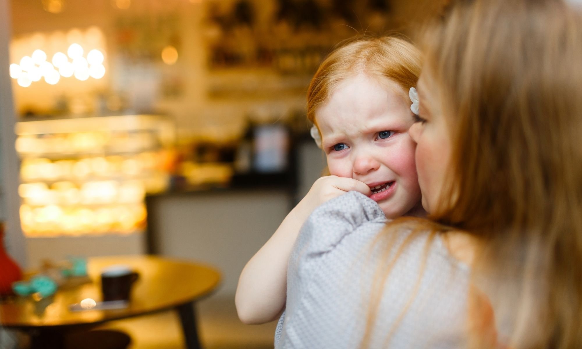 A child crying hanging onto the mother (not wanting to leave)