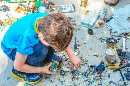 Toddler crouched and playing with recycled plastic pieces
