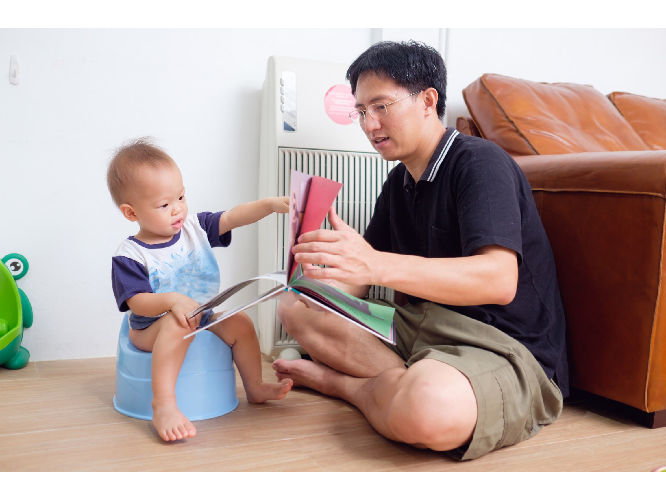 Dad reads to his child in the living room while they start to potty train