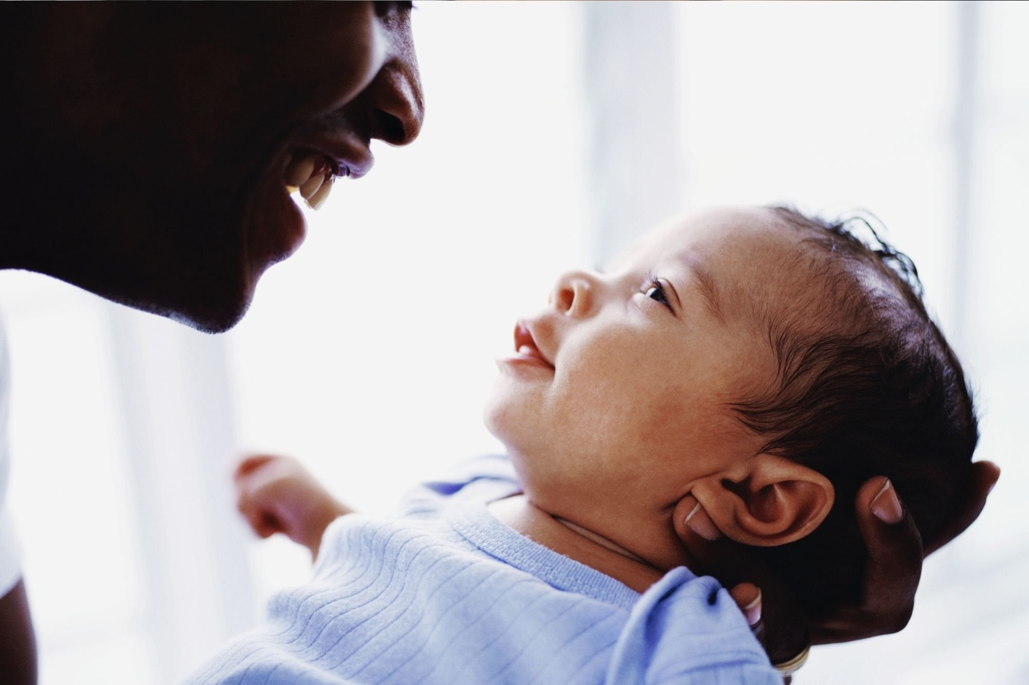 Father playing and looking at his small baby