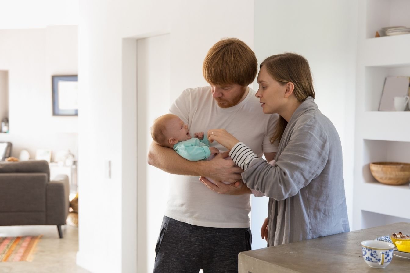 mother holding baby with dad nearby