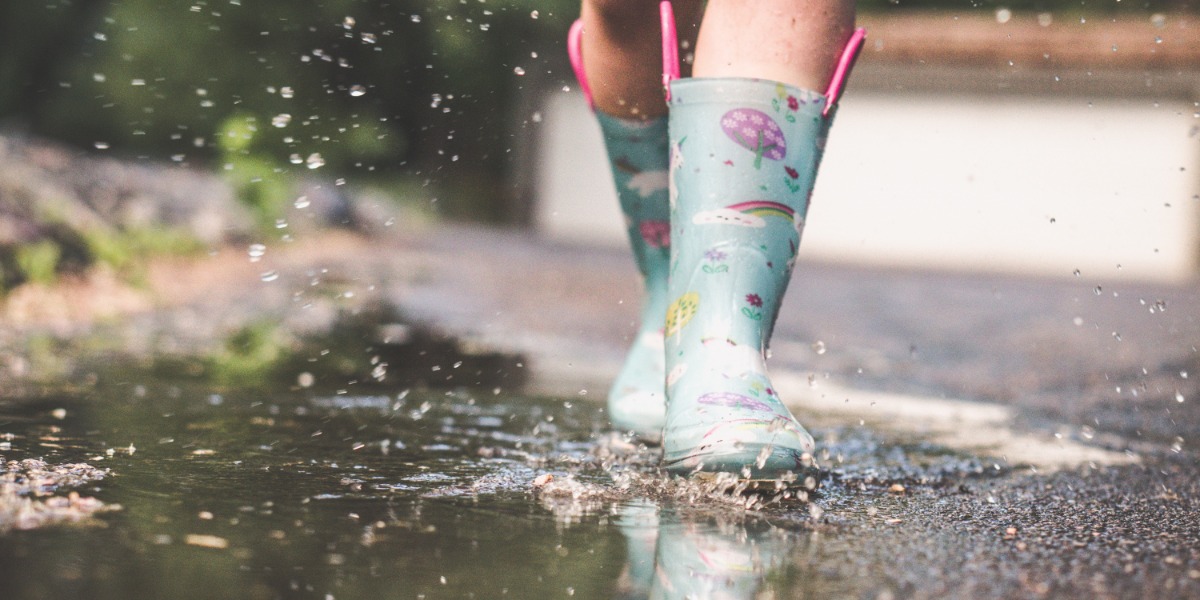 Child splashing in the puddles with wellington boots