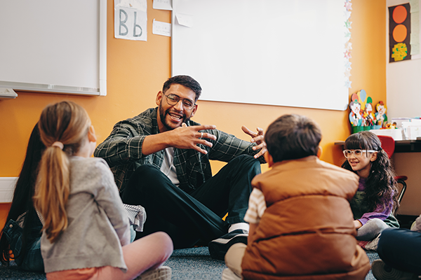 Teacher engaging young children in a circle during a classroom storytelling activity, fostering early learning and social interaction.