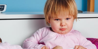 Toddler dressed in a long sleeve pink top making a funny face