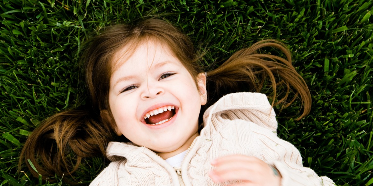 Happy toddler laying on green grass during the summer