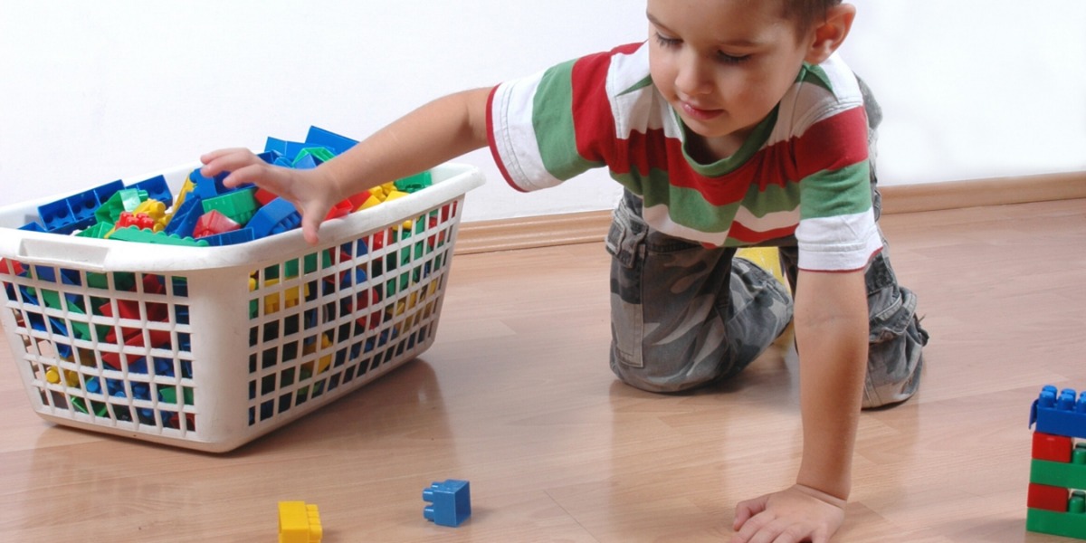 Child tidying up their coloured LEGO into a basket