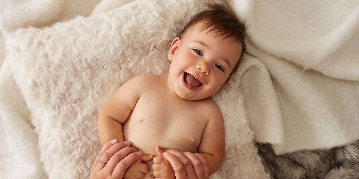 smiling baby lying on a fluffy pillow