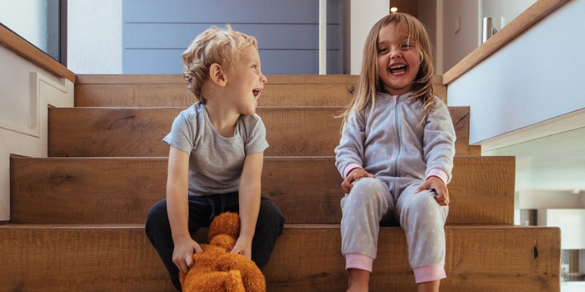 Two toddlers sat on a step at home laughing together