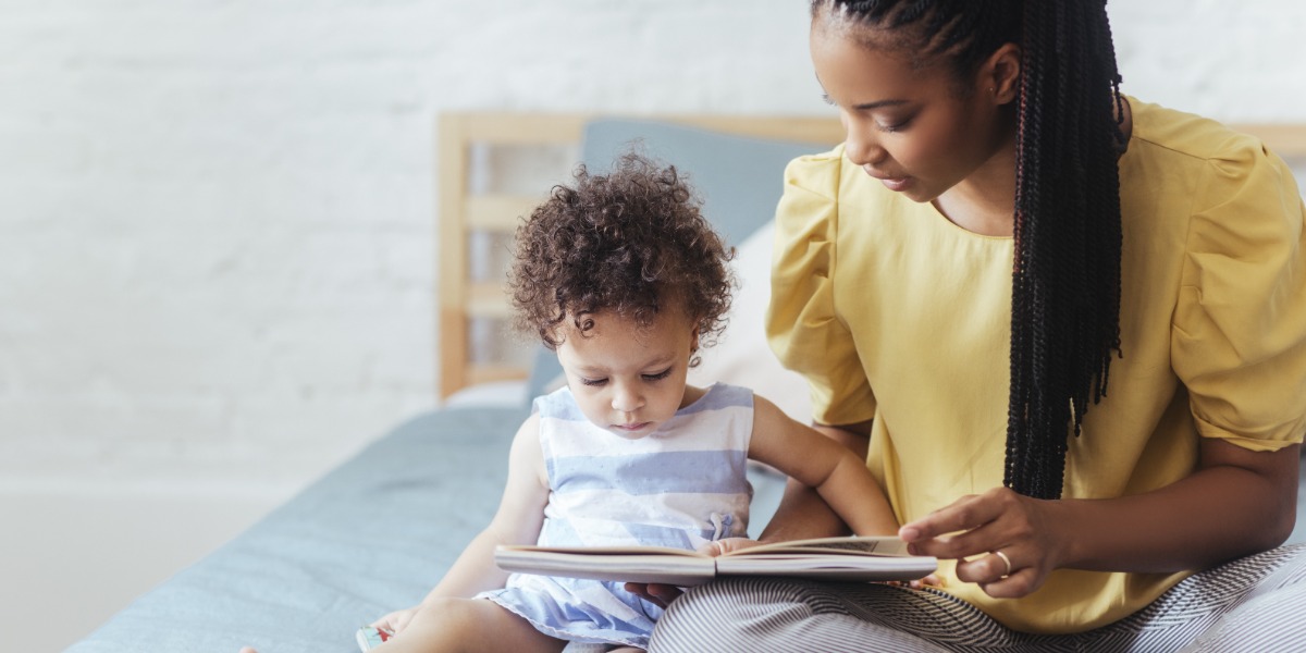 Parent sat reading a book to a toddler