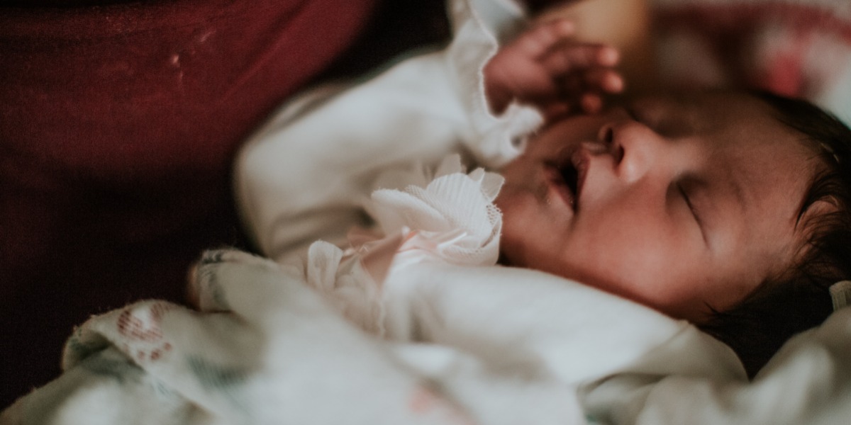 Baby in a white bodysuit resting peacefully