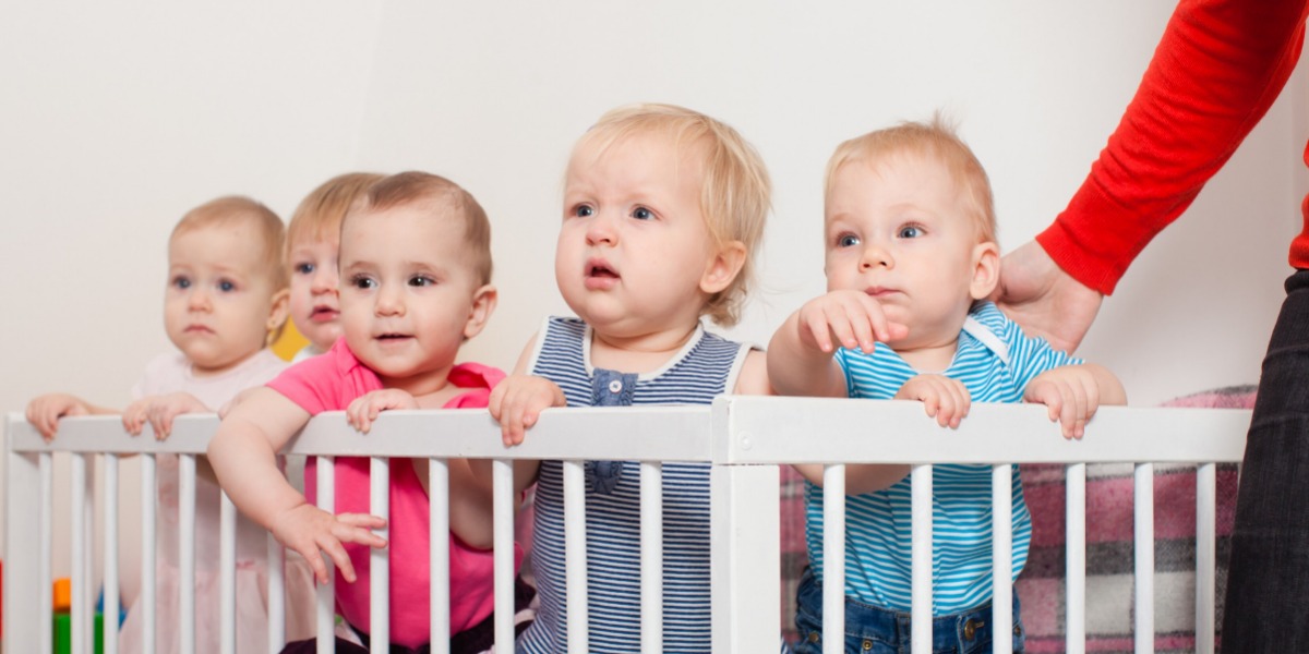 Toddlers standing inside a play pen
