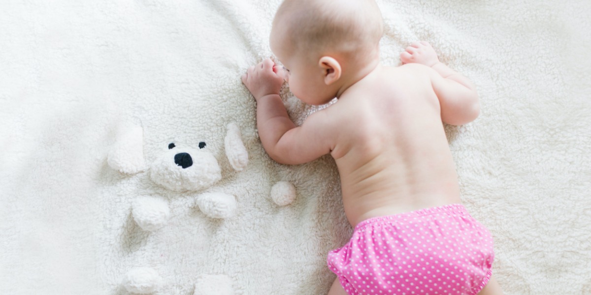 Baby laying on their tummy wearing a pink spotty pants