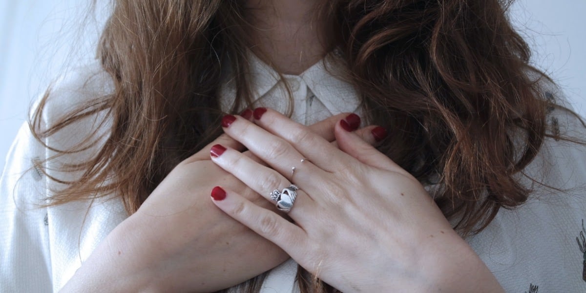 woman stood still holding her hands over her heart