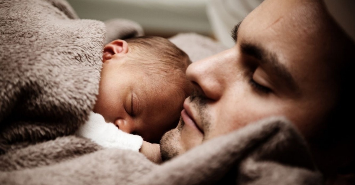 Dad and baby sleeping under a blanket