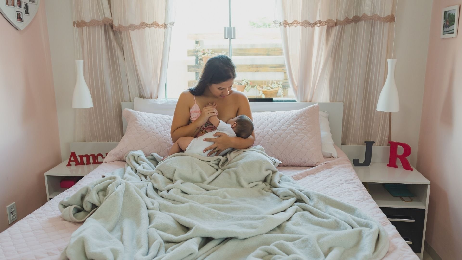 Mother breastfeeding her baby girl in bed