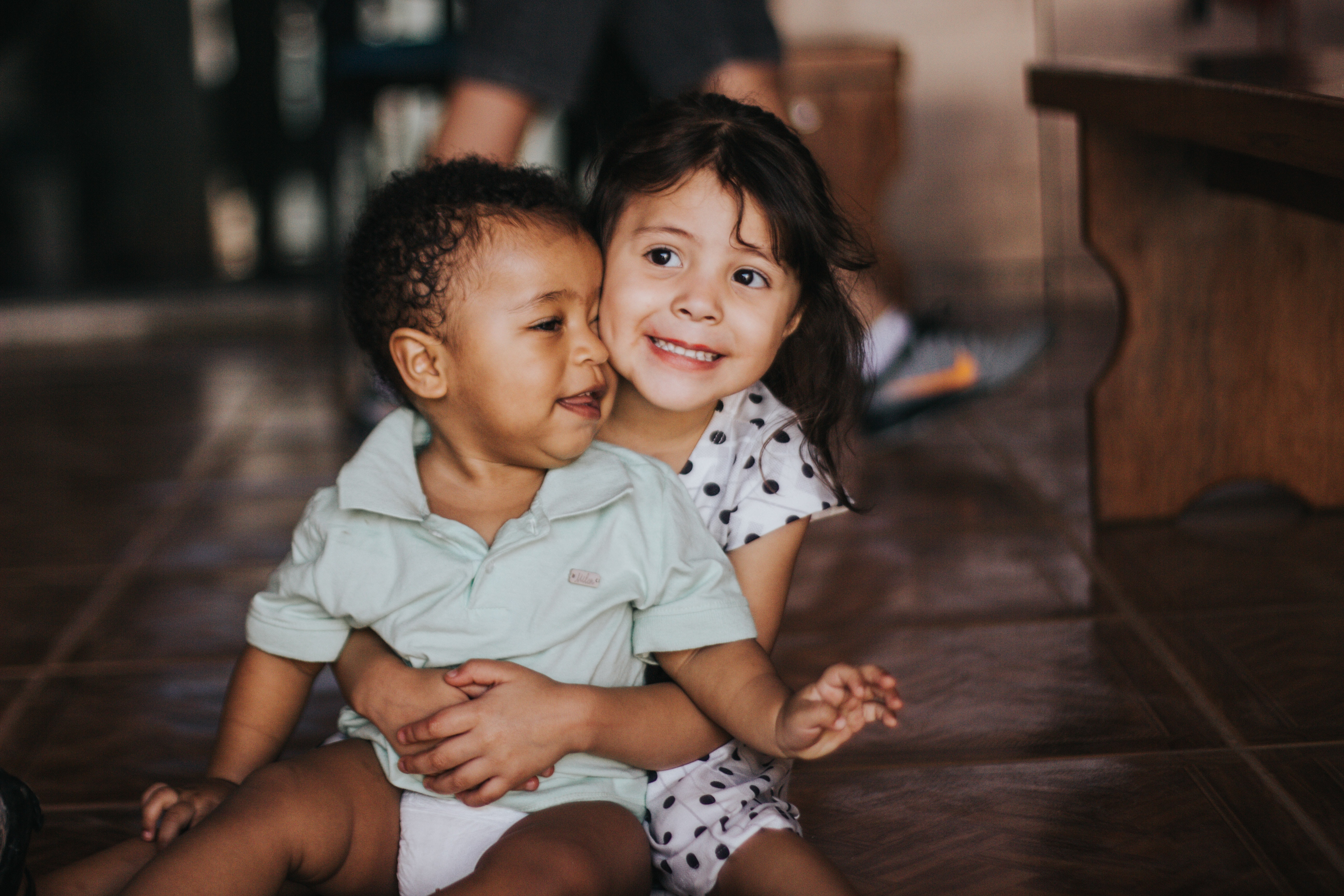 Sister happily hugging and supporting her baby brother from behind