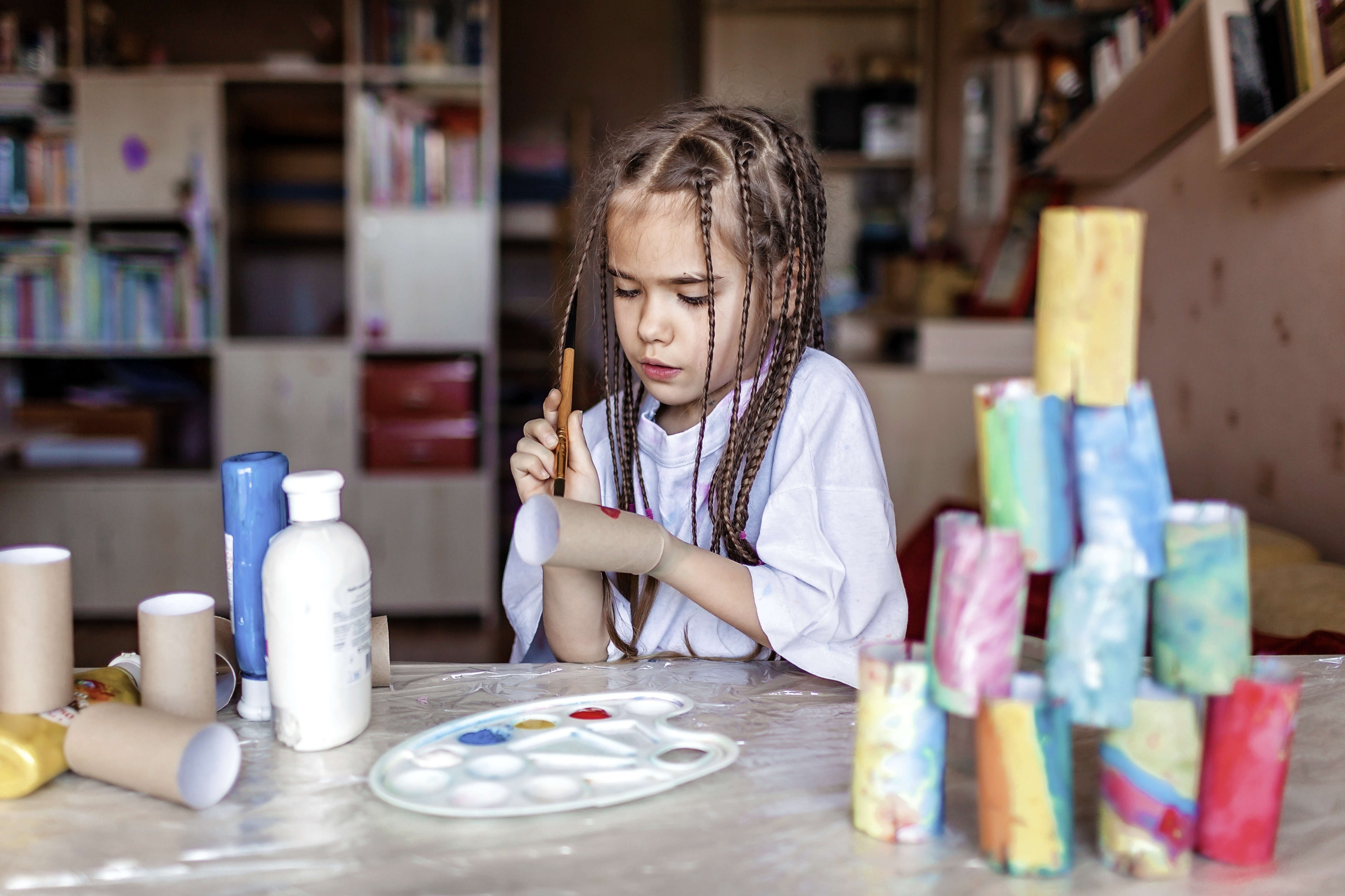 Child painting a cardboard toilet roll with coloured paints