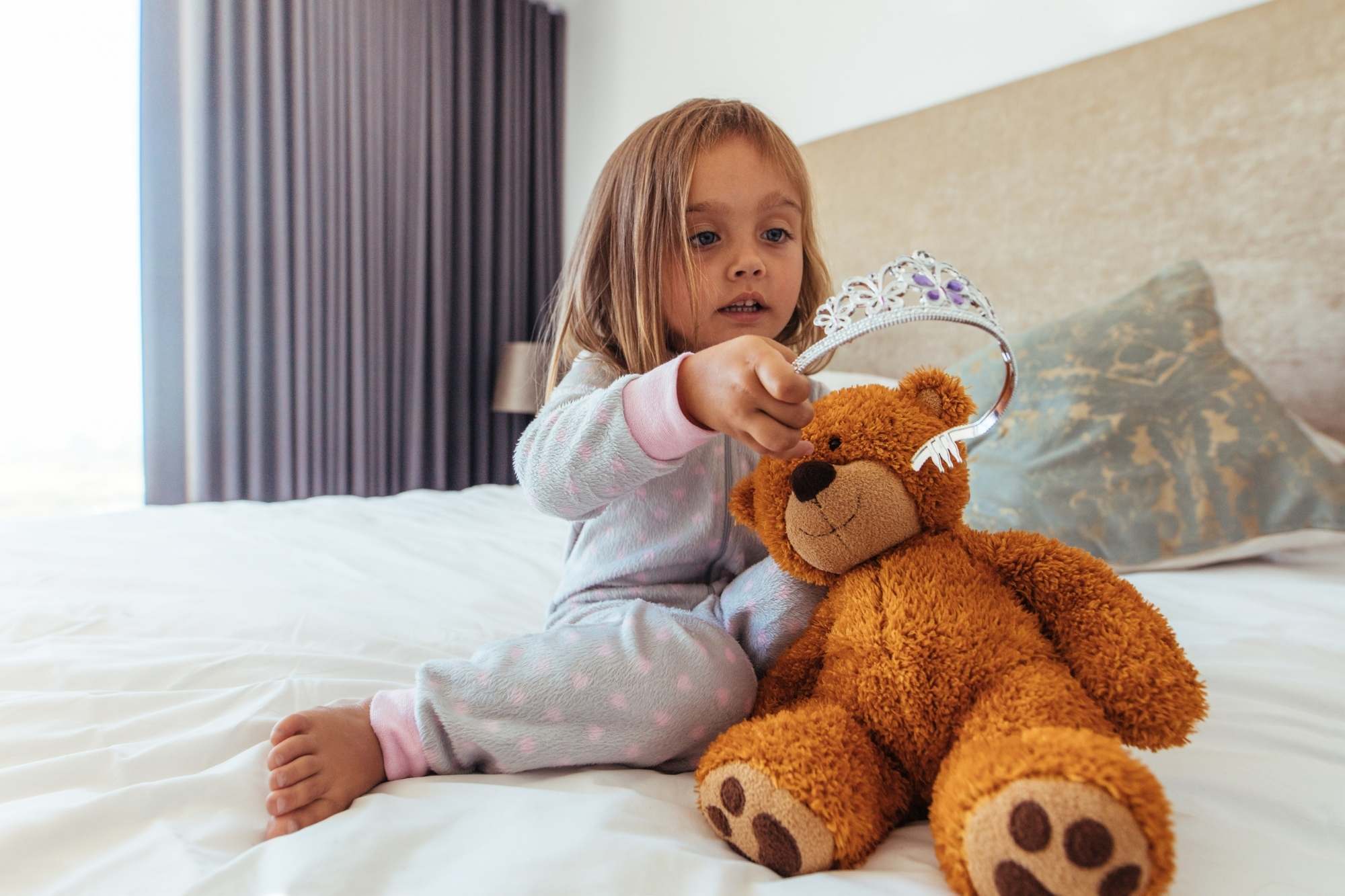 Little girl putting a crown on her teddy