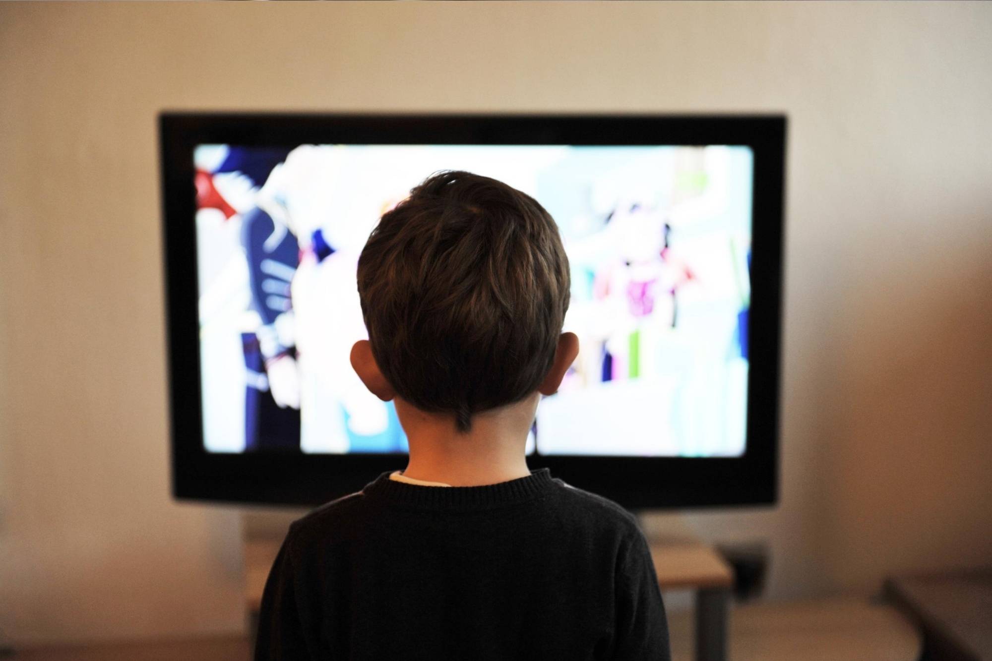 Kid in a black top watching TV at home